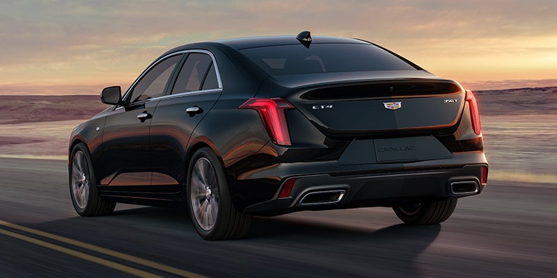 Rear view of a black Cadillac CT4 driving sunset.