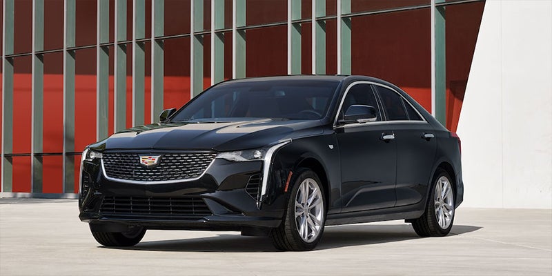 Black Cadillac CT4 sedan parked outside a modern building.